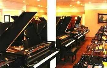 A row of pianos are lined up in a room.