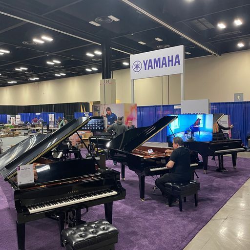 A man is playing a piano in front of a sign that says yamaha