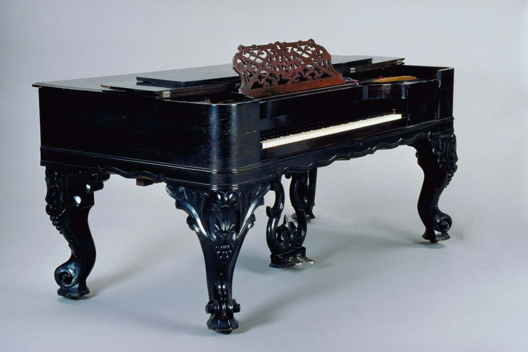 A black piano with a cushion on top of it