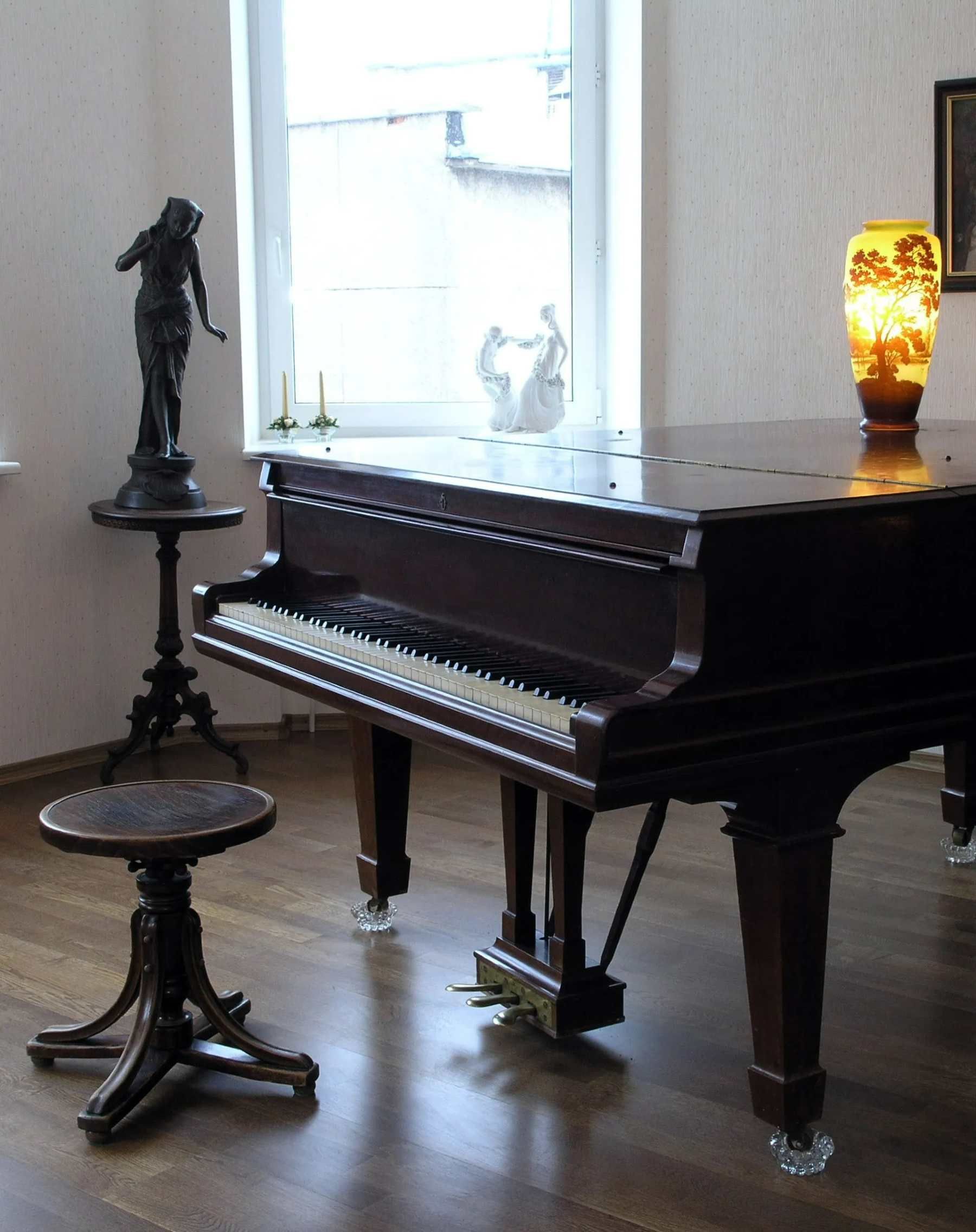 A piano in a room with a lamp and a statue