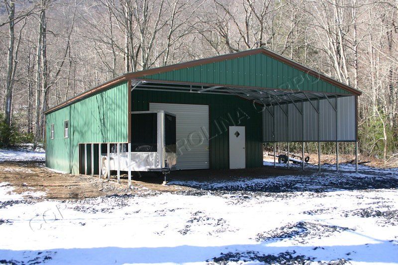 A green metal building is sitting in the middle of a snowy field.