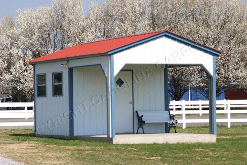 A small white building with a red roof and a bench underneath it