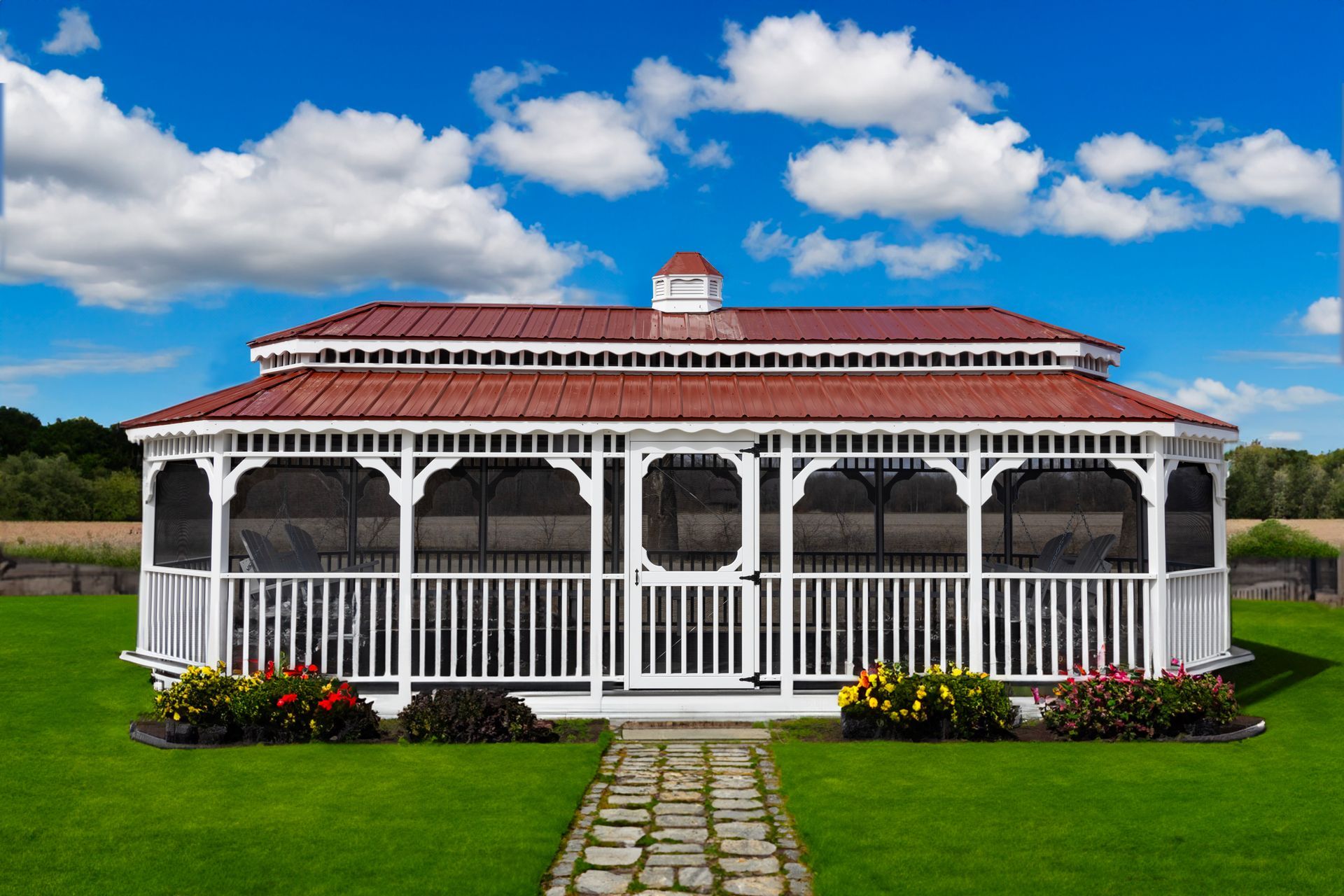 A white gazebo with a screened in porch is sitting in the middle of a lush green field.