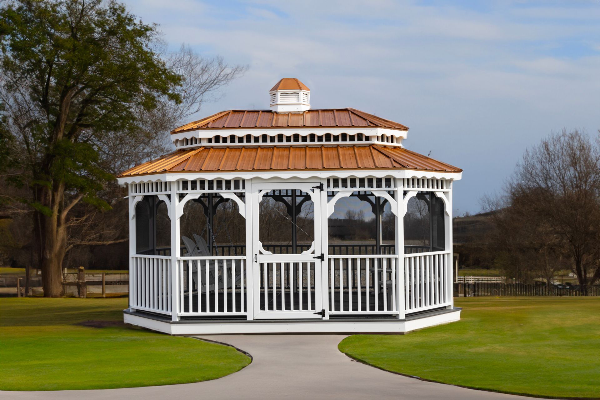 A white gazebo with a screened in porch is sitting on top of a lush green field.
