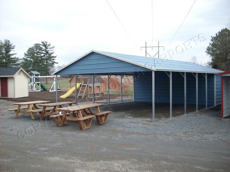 A blue carport with a picnic table in front of it