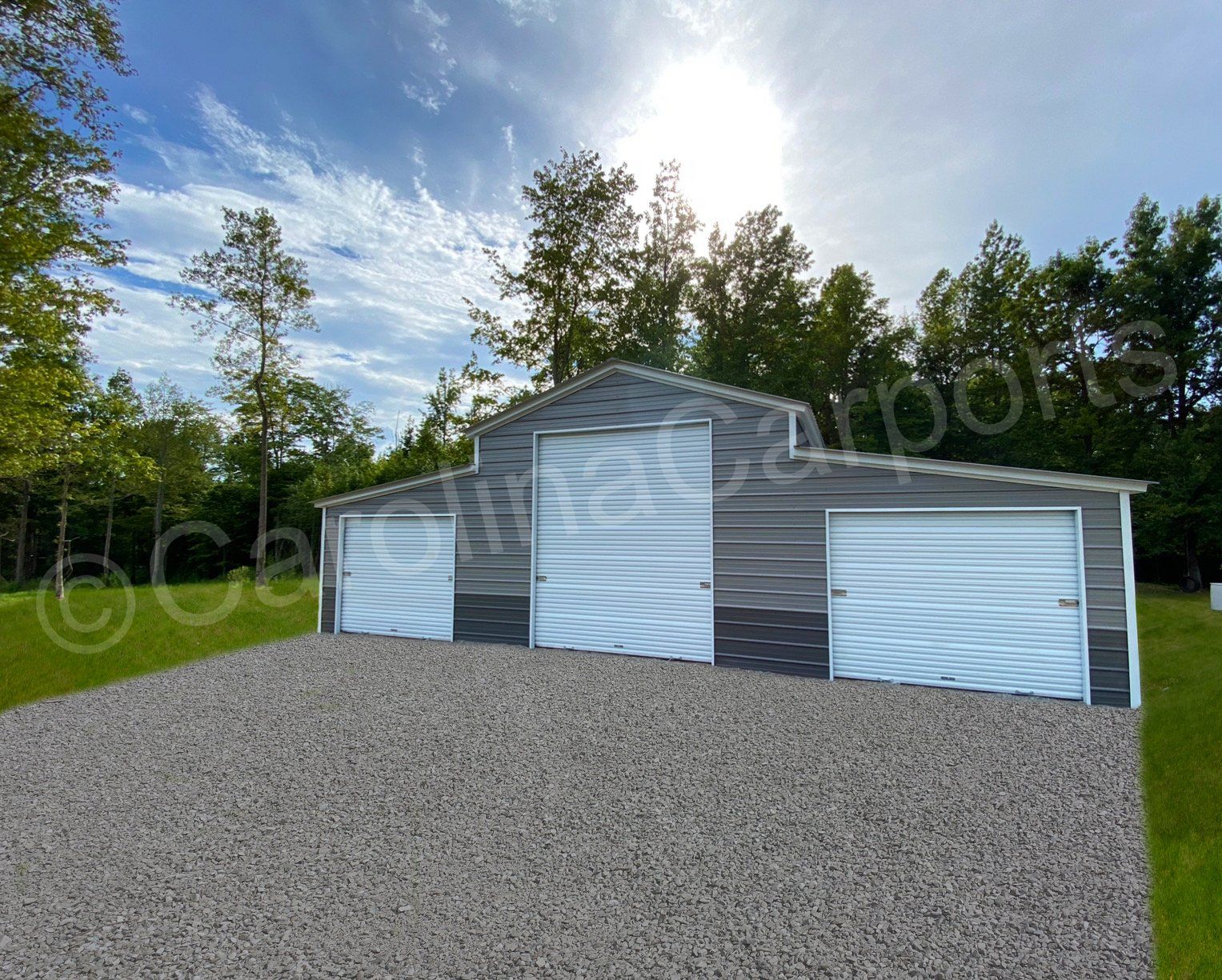 A garage with three garage doors and a gravel driveway in front of it.