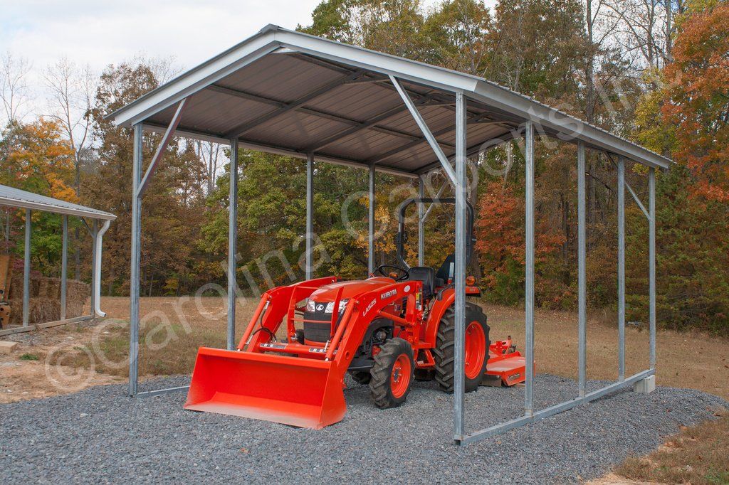 A red tractor is parked under a metal shed.