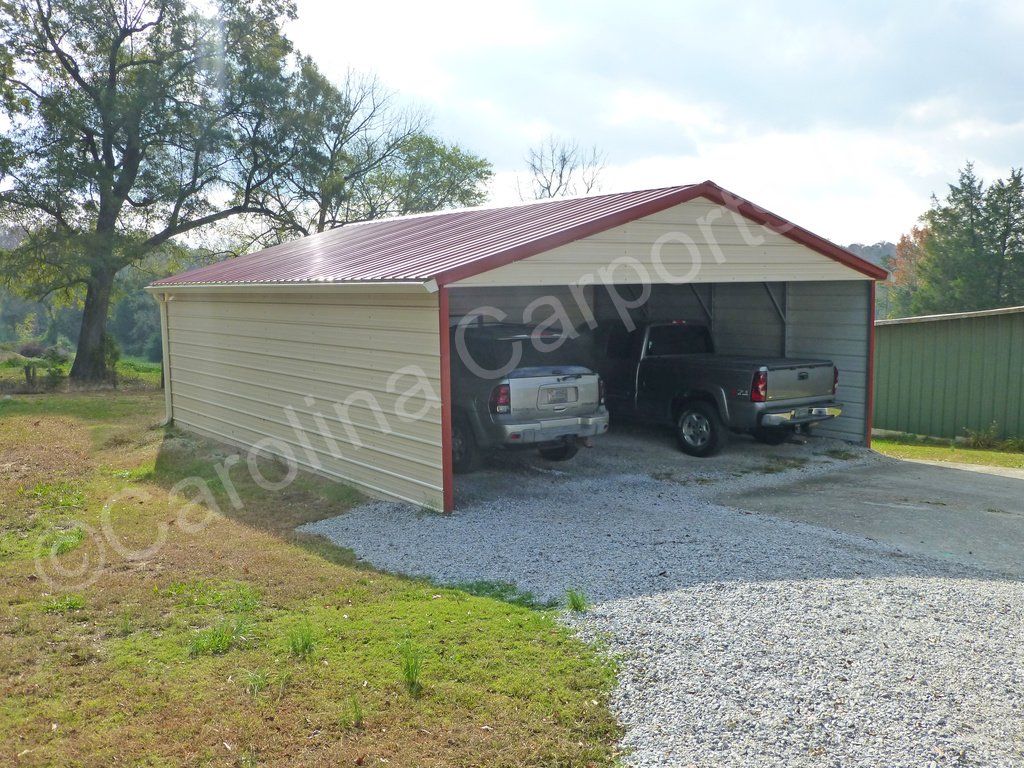 Two cars are parked in a carport with a red roof.