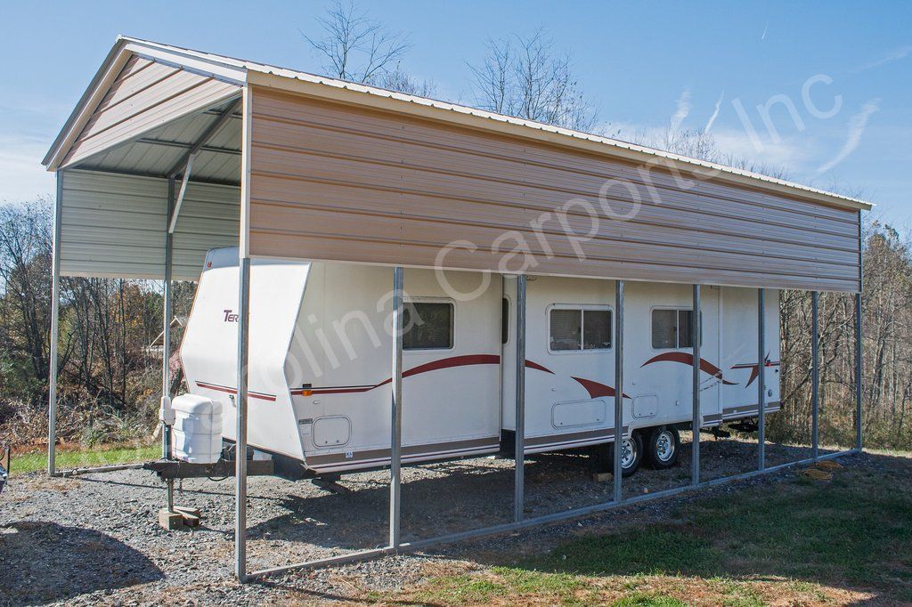 A white trailer is parked under a carport.