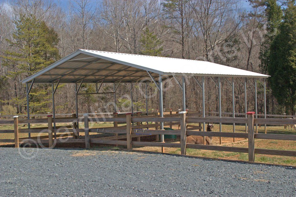 A horse stable with a white roof and a wooden fence