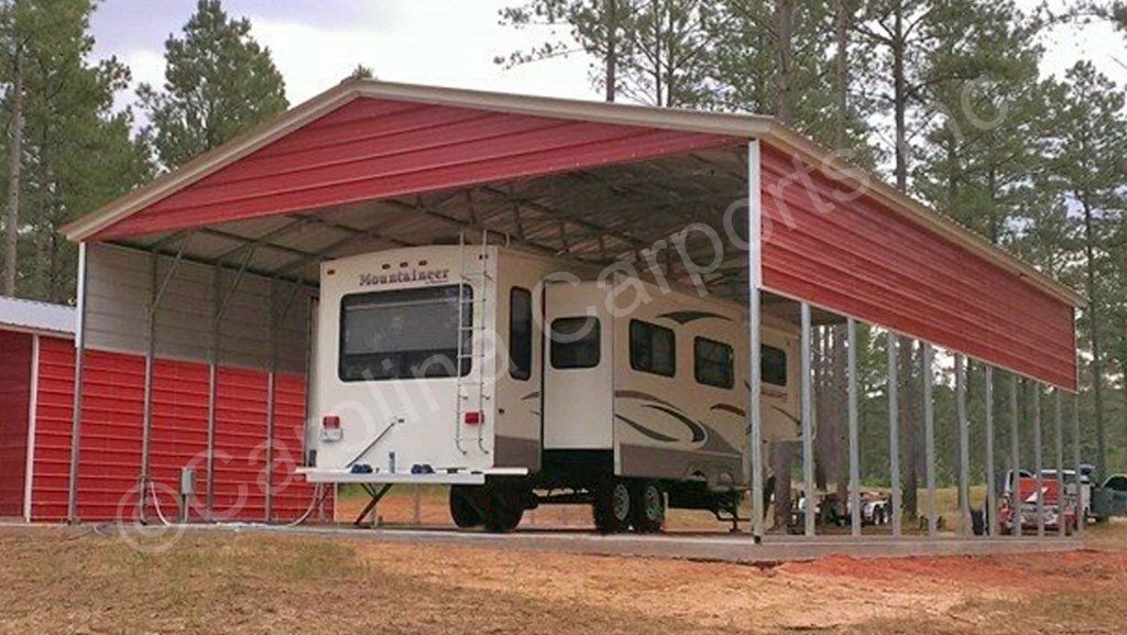 A white rv is parked under a red carport