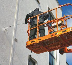 Man cleaning an establishment wall using a power washer