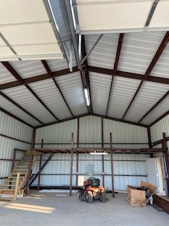 A tractor is parked inside of a metal building