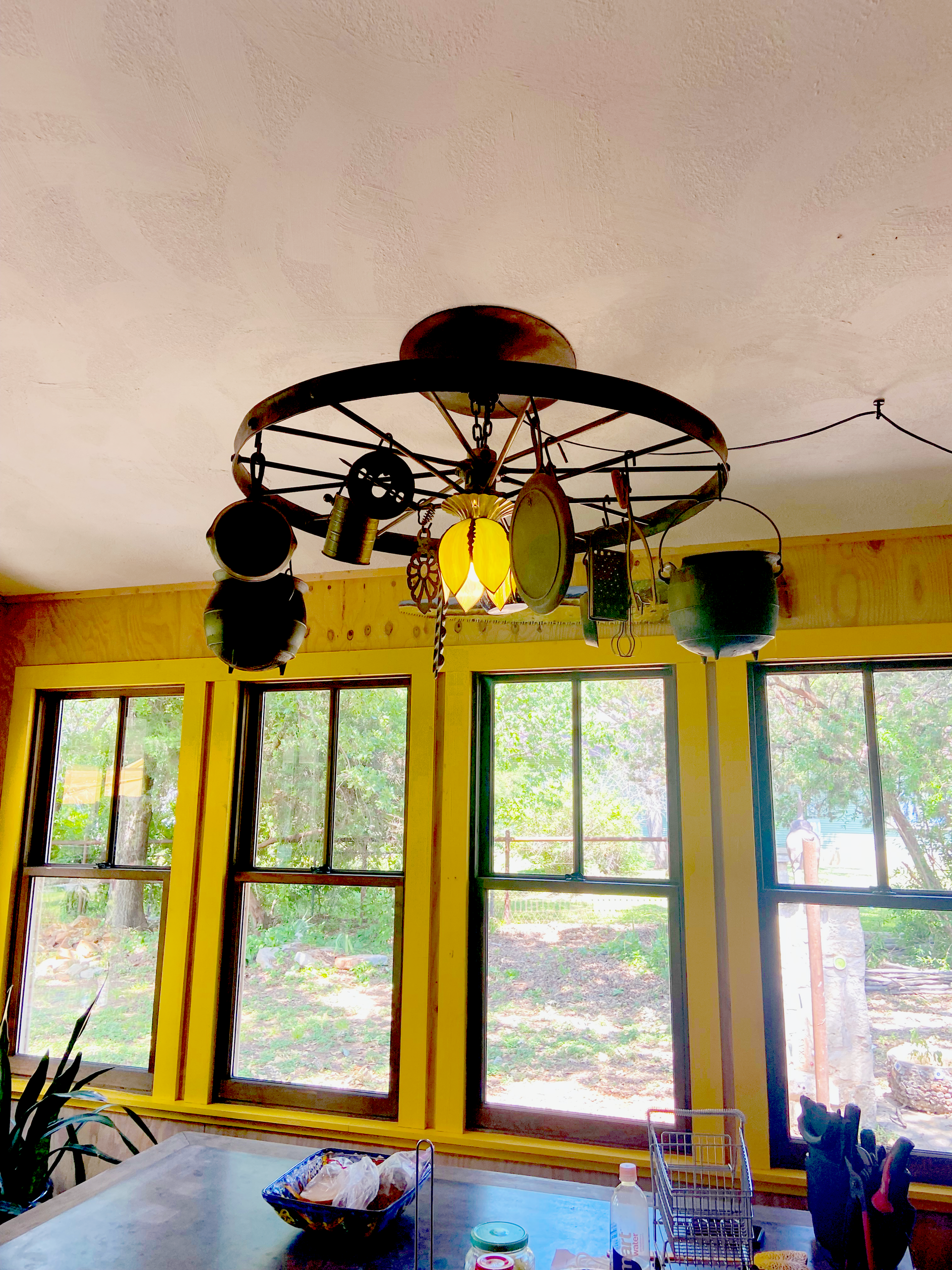 A kitchen with a chandelier made out of a wagon wheel
