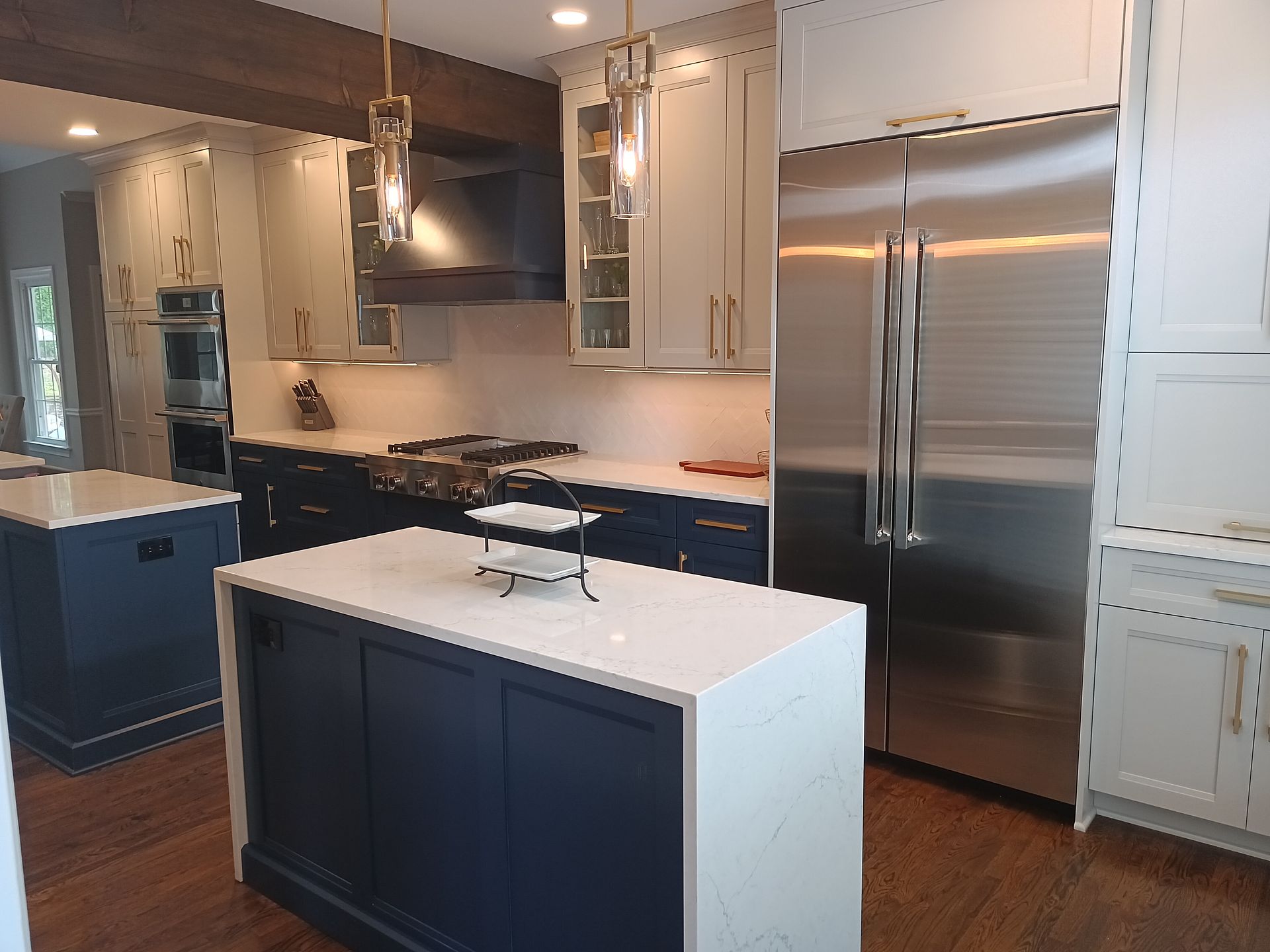 Modern kitchen with blue and white cabinets, stainless steel fridge, and two islands.