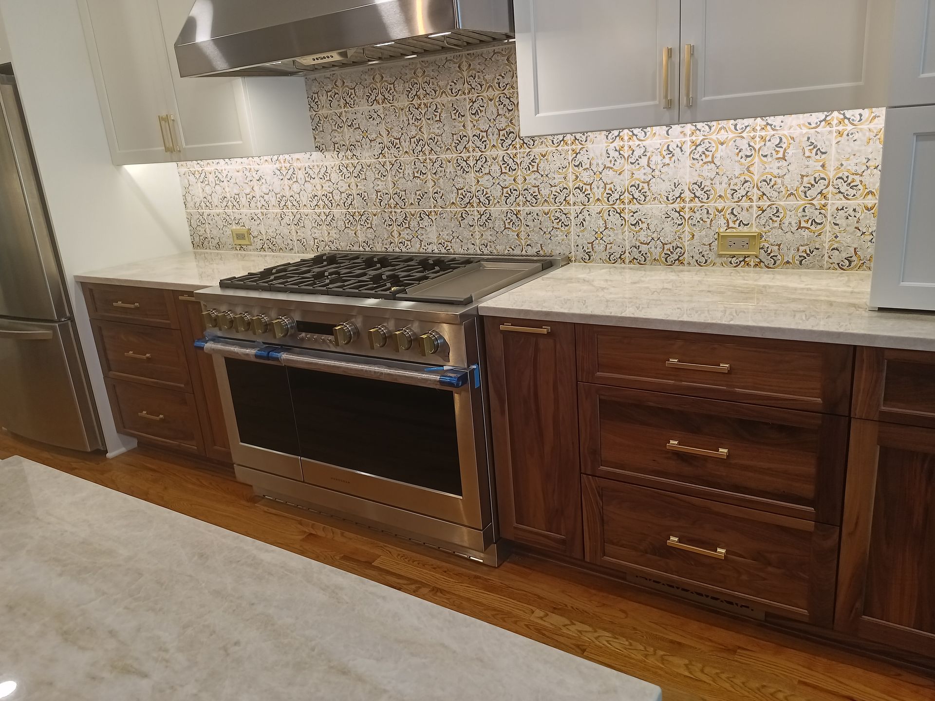 Kitchen with stainless steel range, dark wood cabinets, light countertops, and patterned backsplash.