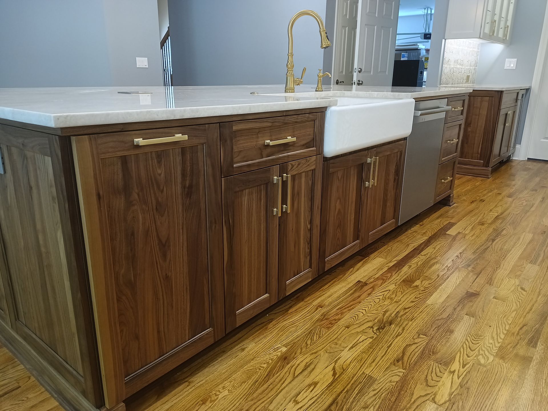 Kitchen island with wood cabinets, white countertop, and gold faucet.