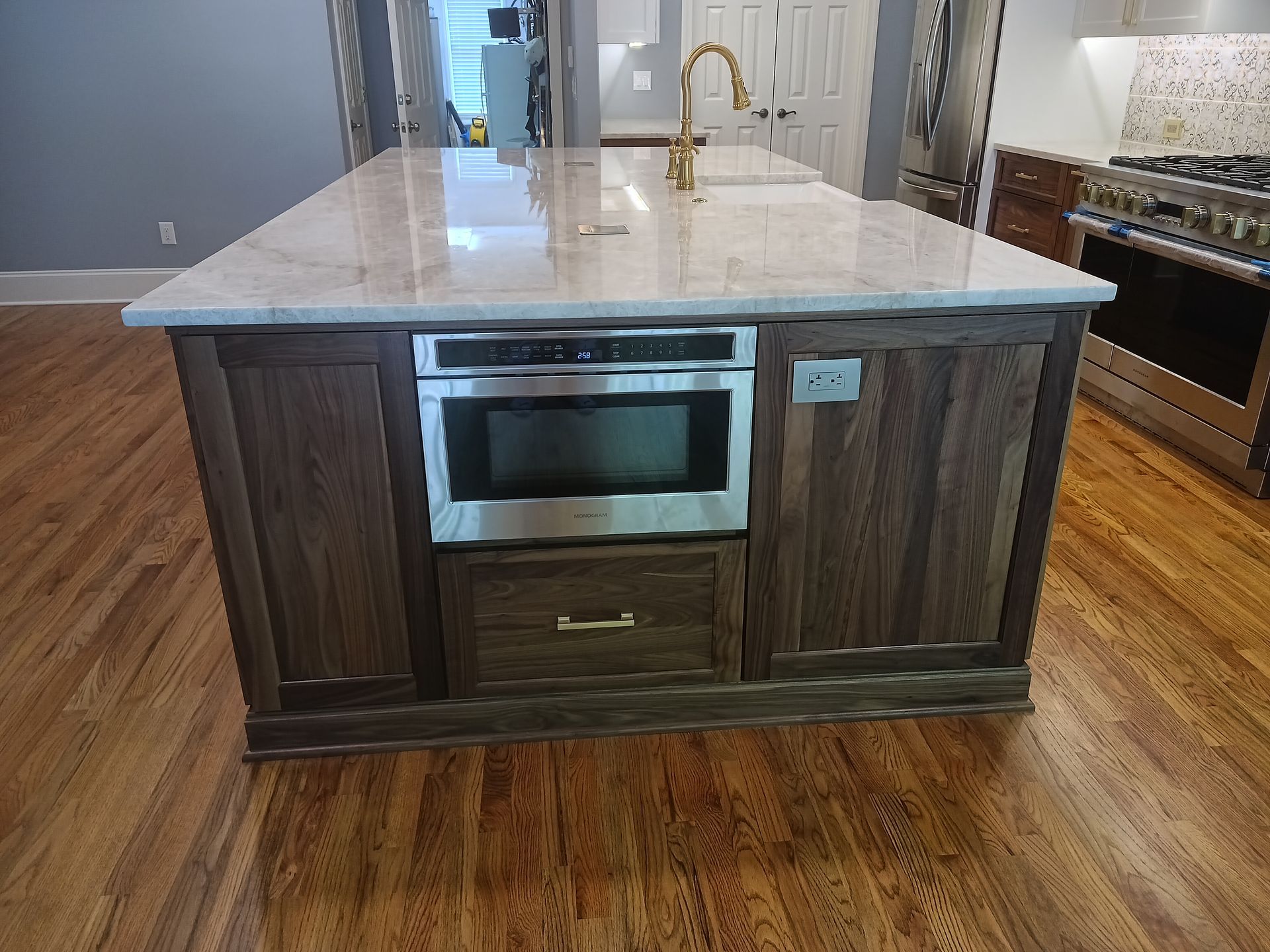Kitchen island with a built-in microwave and drawer, set on hardwood flooring.