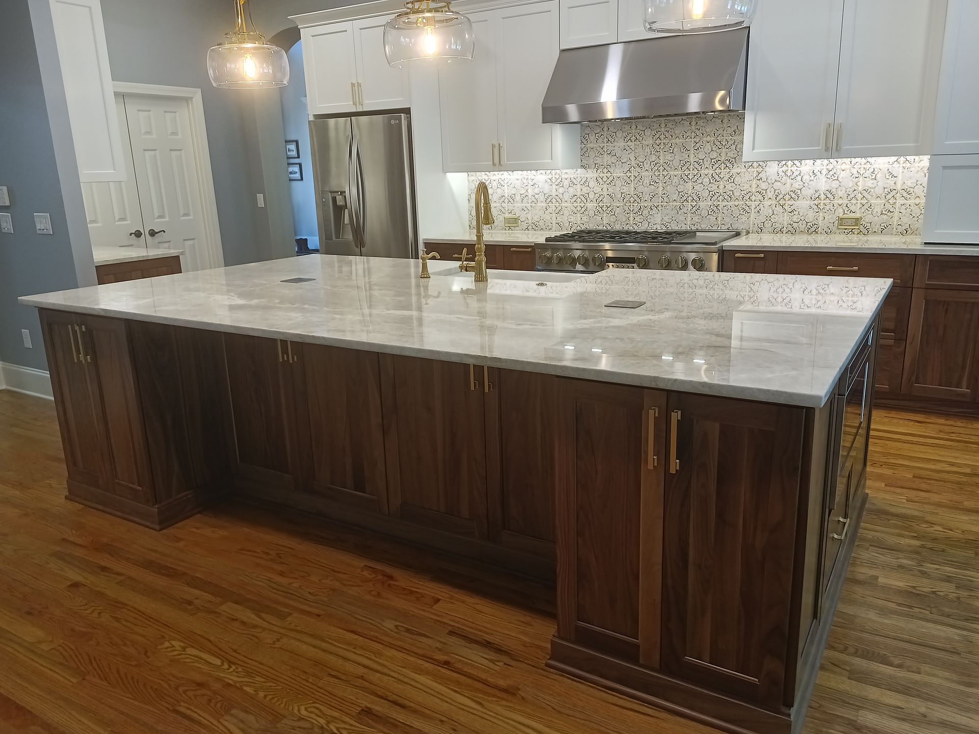 Large kitchen island with dark wood cabinets, light countertop, and gold hardware.