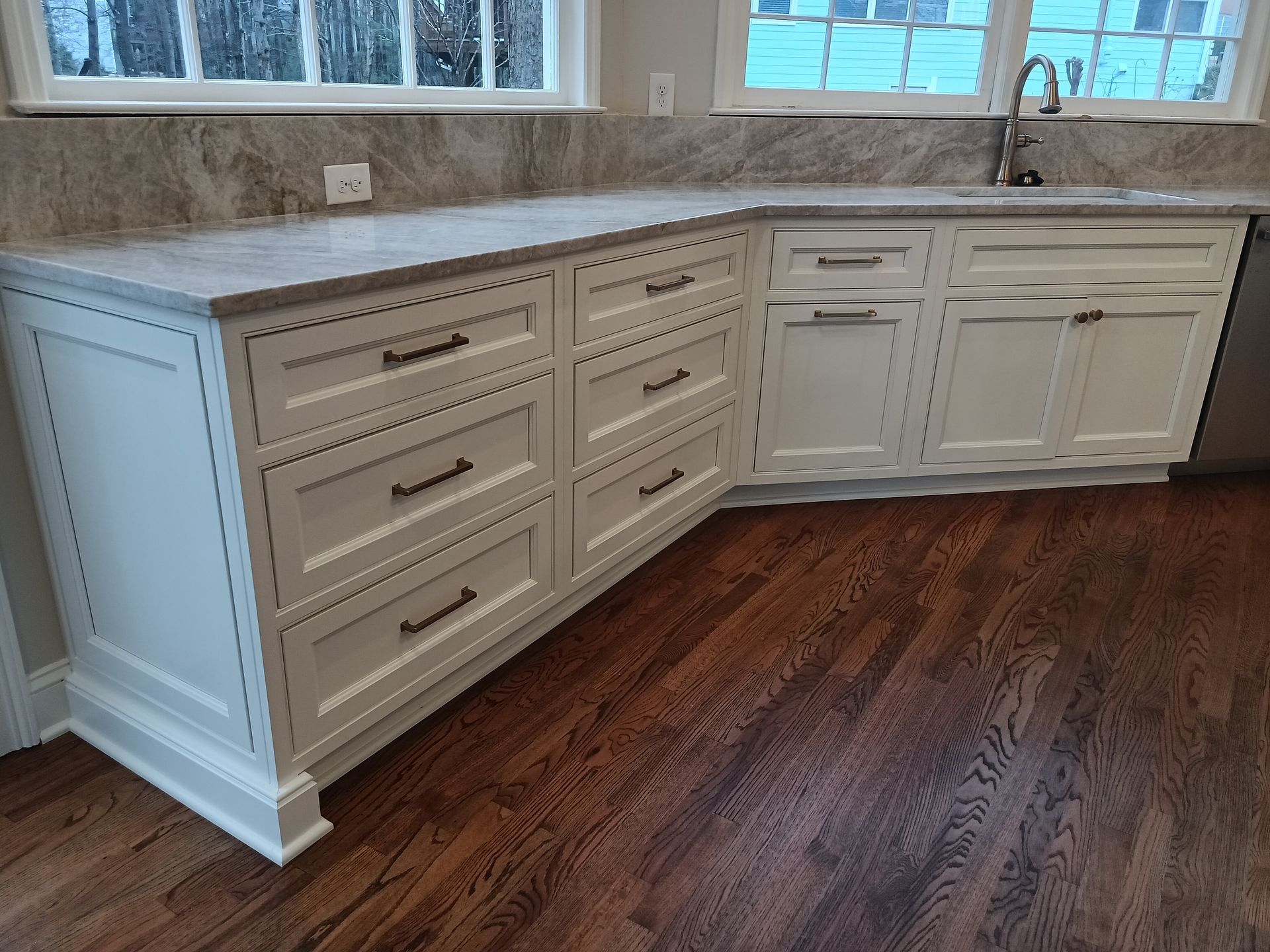 White kitchen cabinets with dark hardware and wood floors.