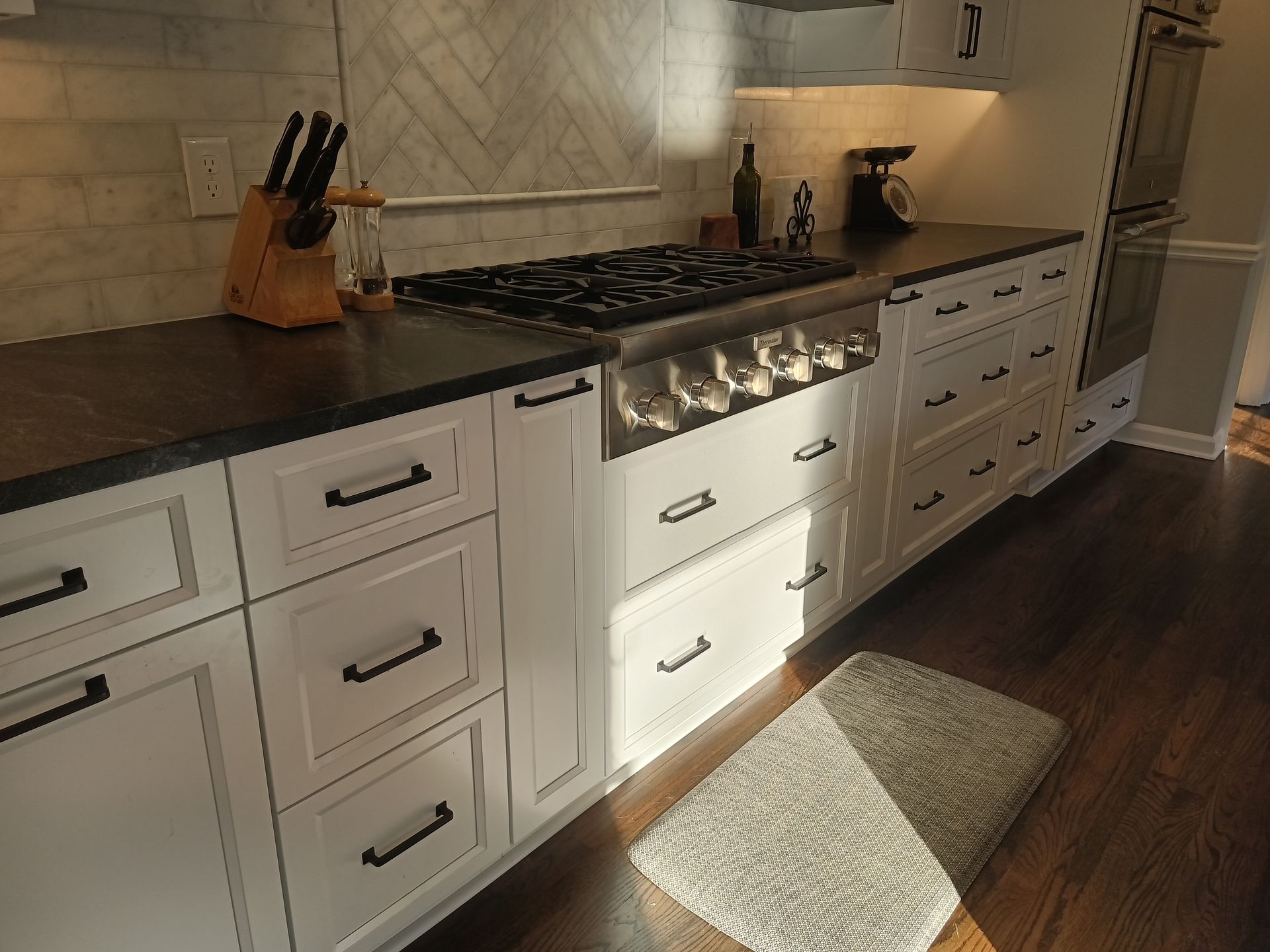 White kitchen cabinets with black countertops and a gas stove.