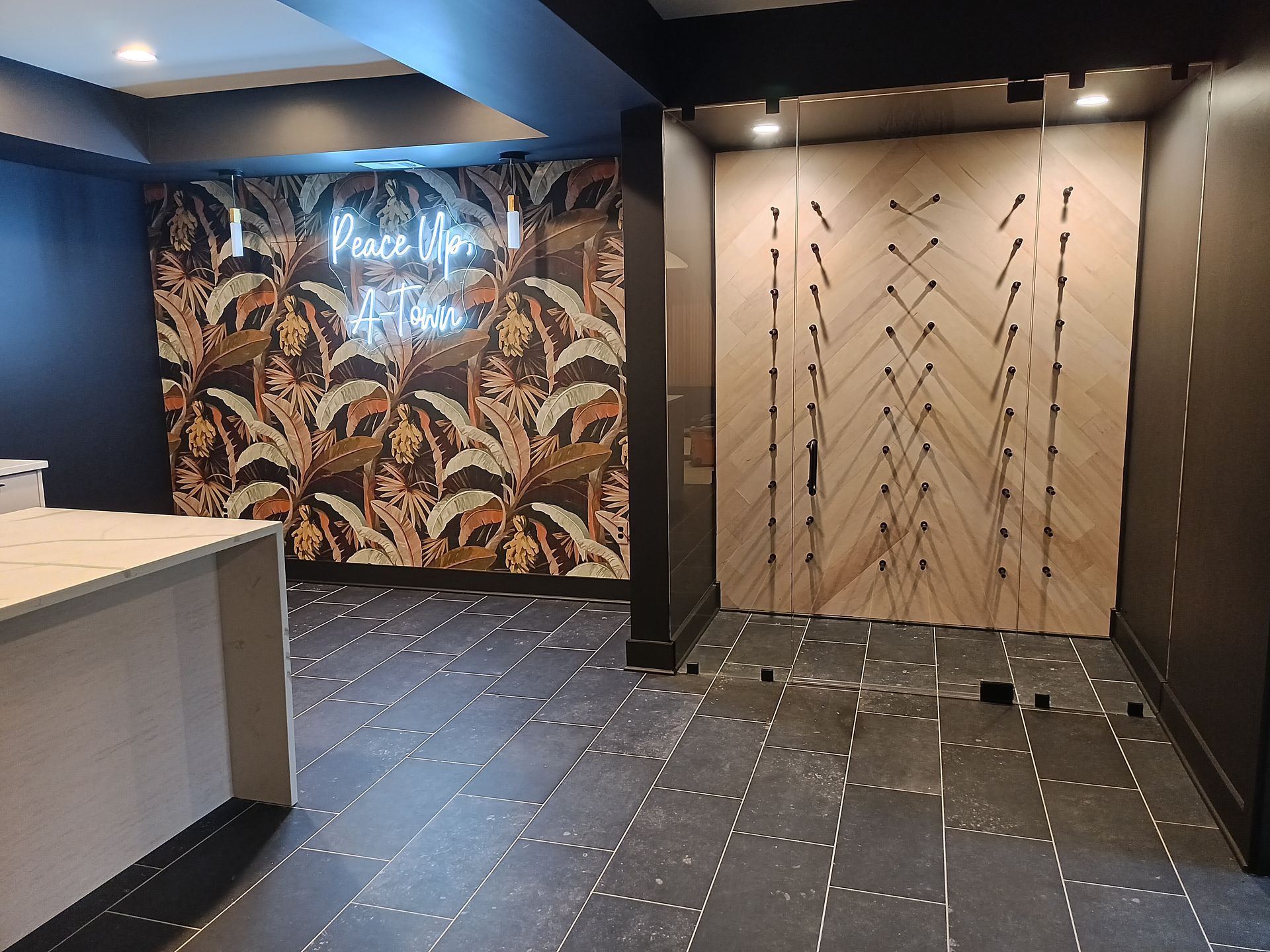 Basement room with patterned wall art and a wooden door design. Black tile floor.