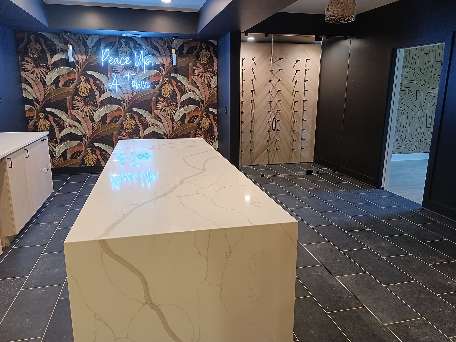 Kitchen with large island, patterned wallpaper, dark walls, light cabinets, and tiled floor.