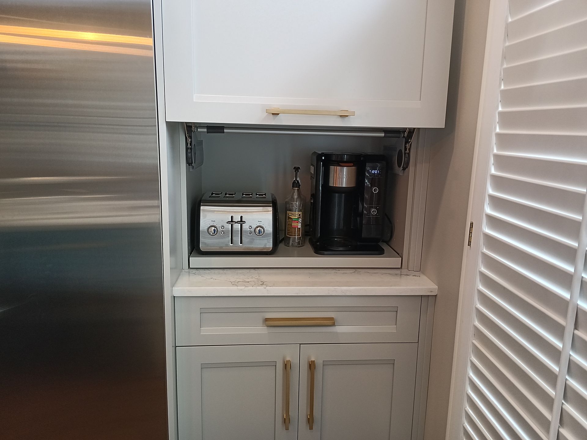 Built-in coffee station with appliances inside gray cabinets, including a toaster and coffee maker.