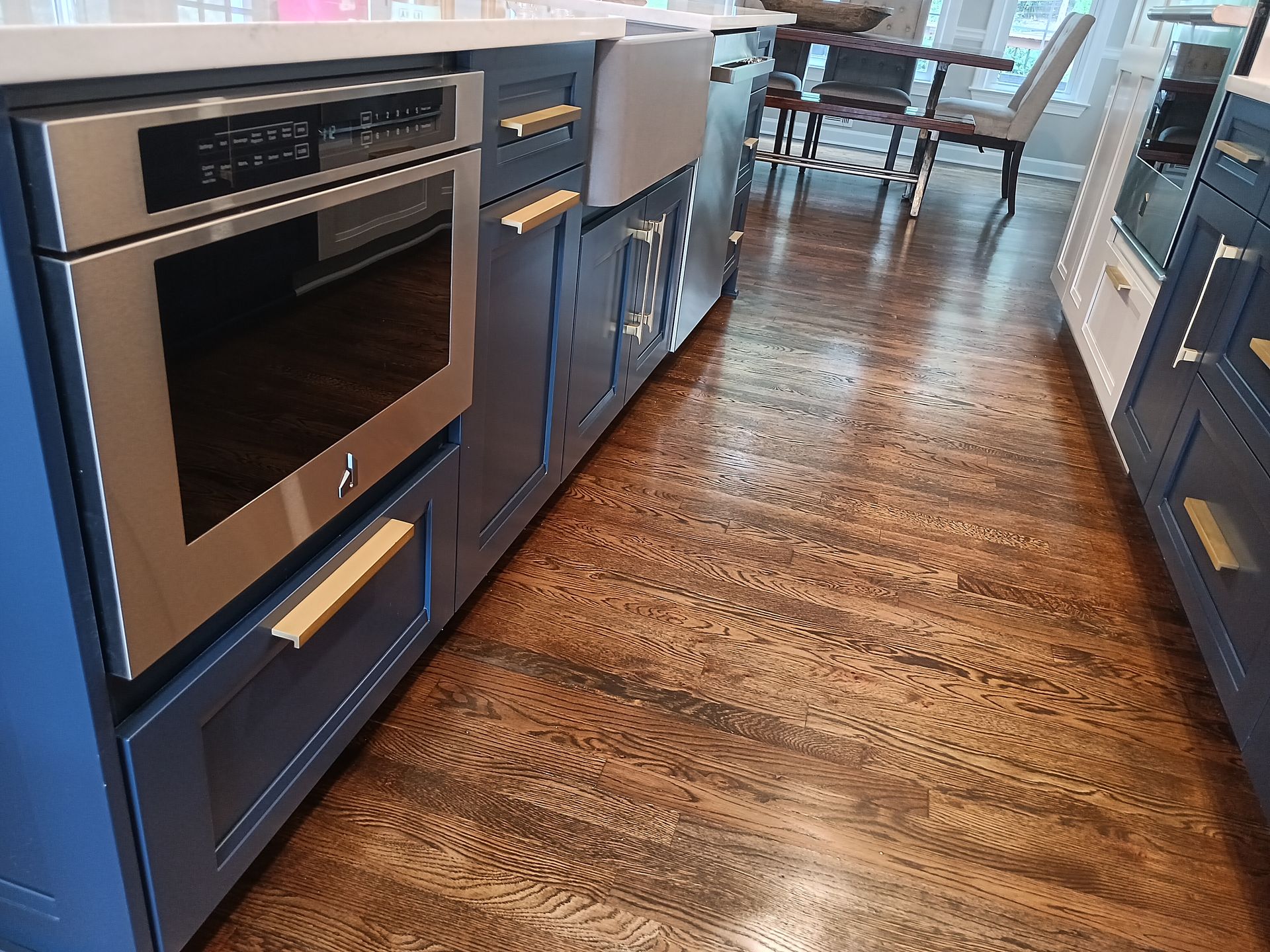 Blue kitchen island with an oven and wooden cabinets, brown hardwood floors.