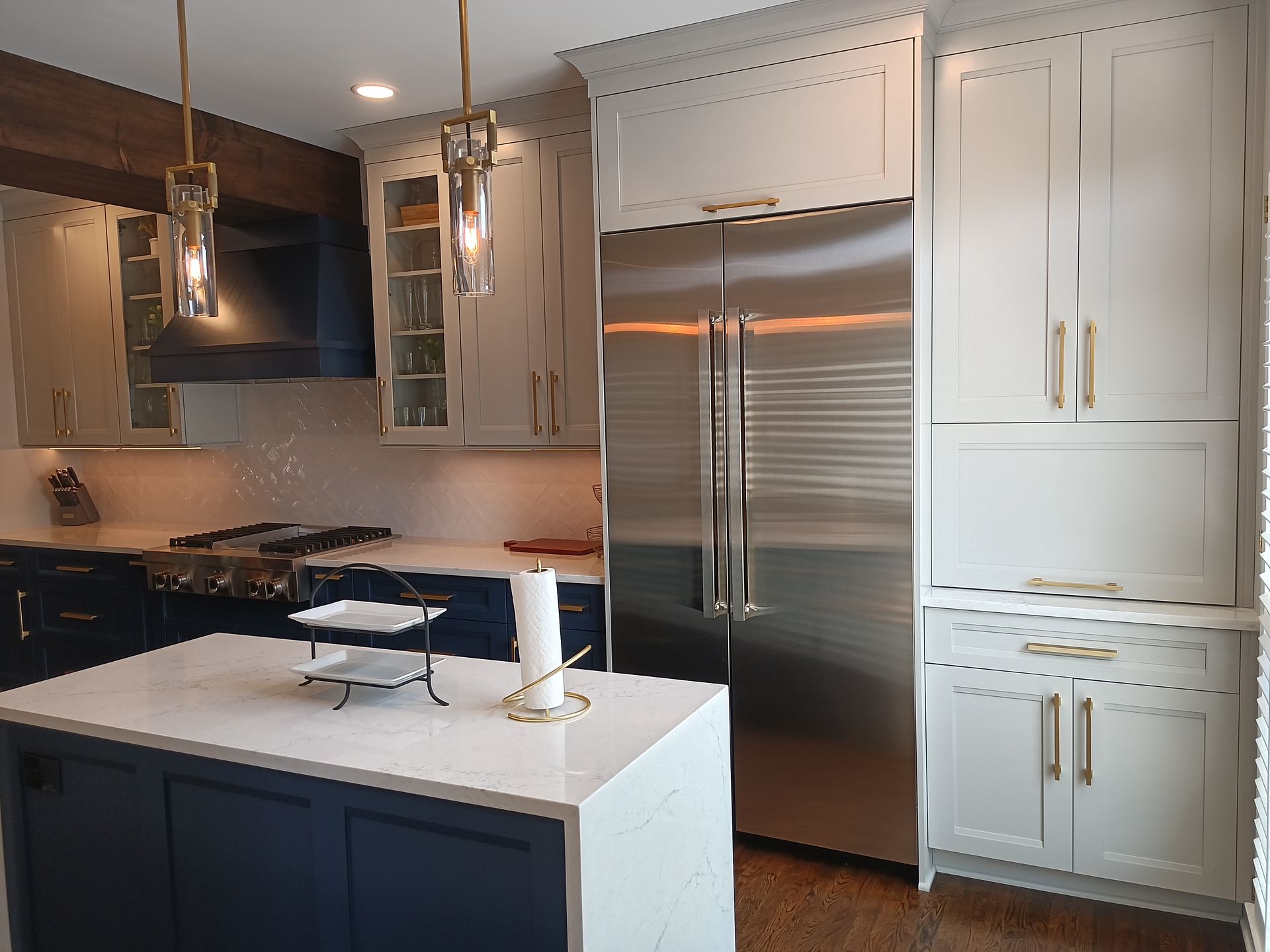 Kitchen with blue and white cabinets, stainless steel fridge, and quartz countertops.