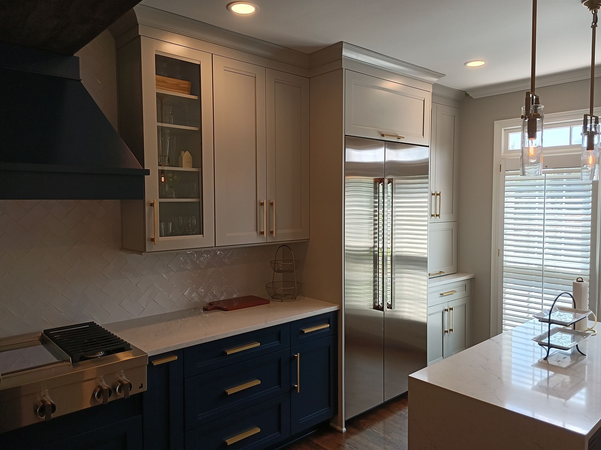 Kitchen with blue and white cabinets, stainless steel fridge, and an island with a sink.