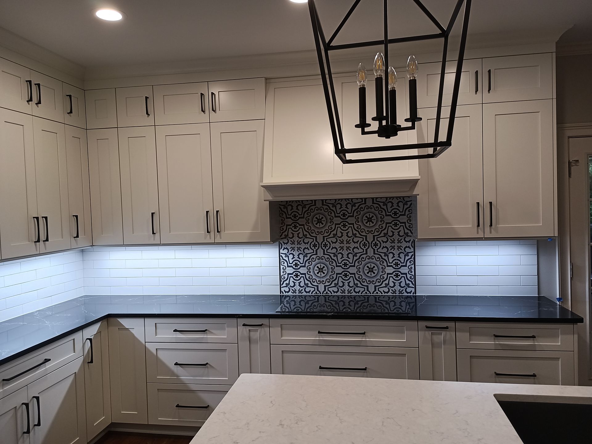 White kitchen with black countertops, backsplash, and light fixtures.
