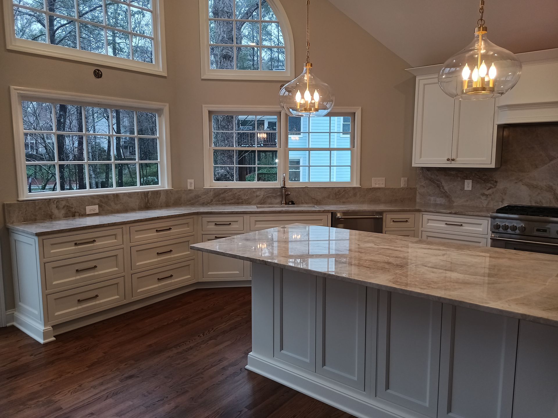 Kitchen with white cabinets, granite countertops, and a large island with pendant lights.