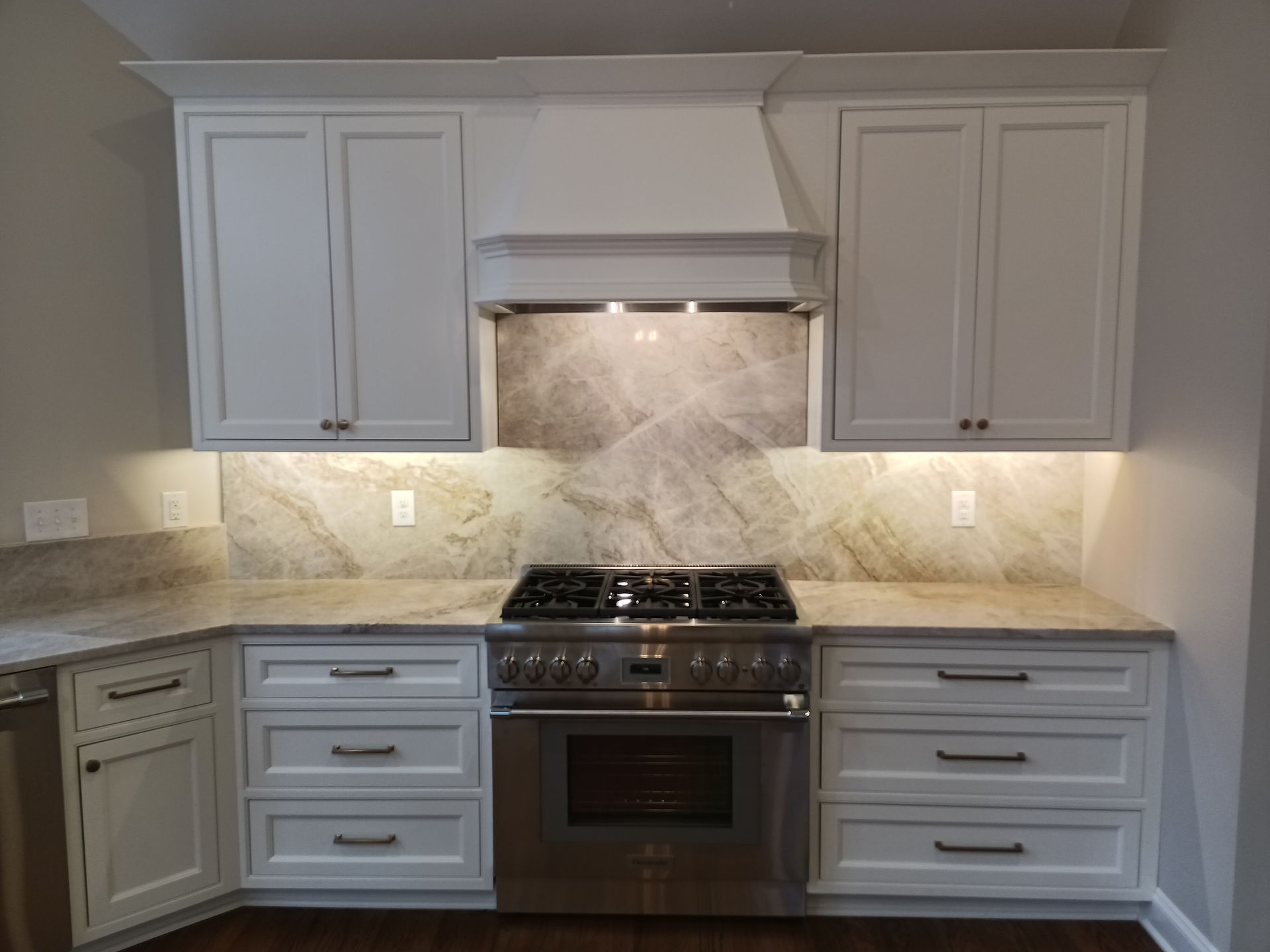 White kitchen cabinets, stainless steel stove, and granite countertops.