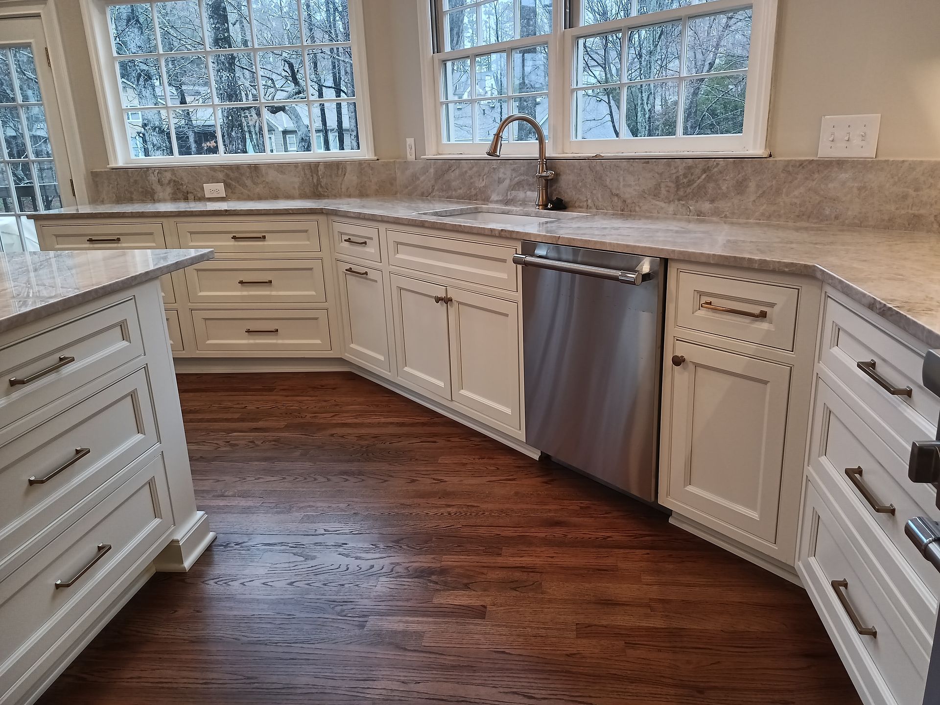 White kitchen cabinets with granite countertops and stainless steel dishwasher.