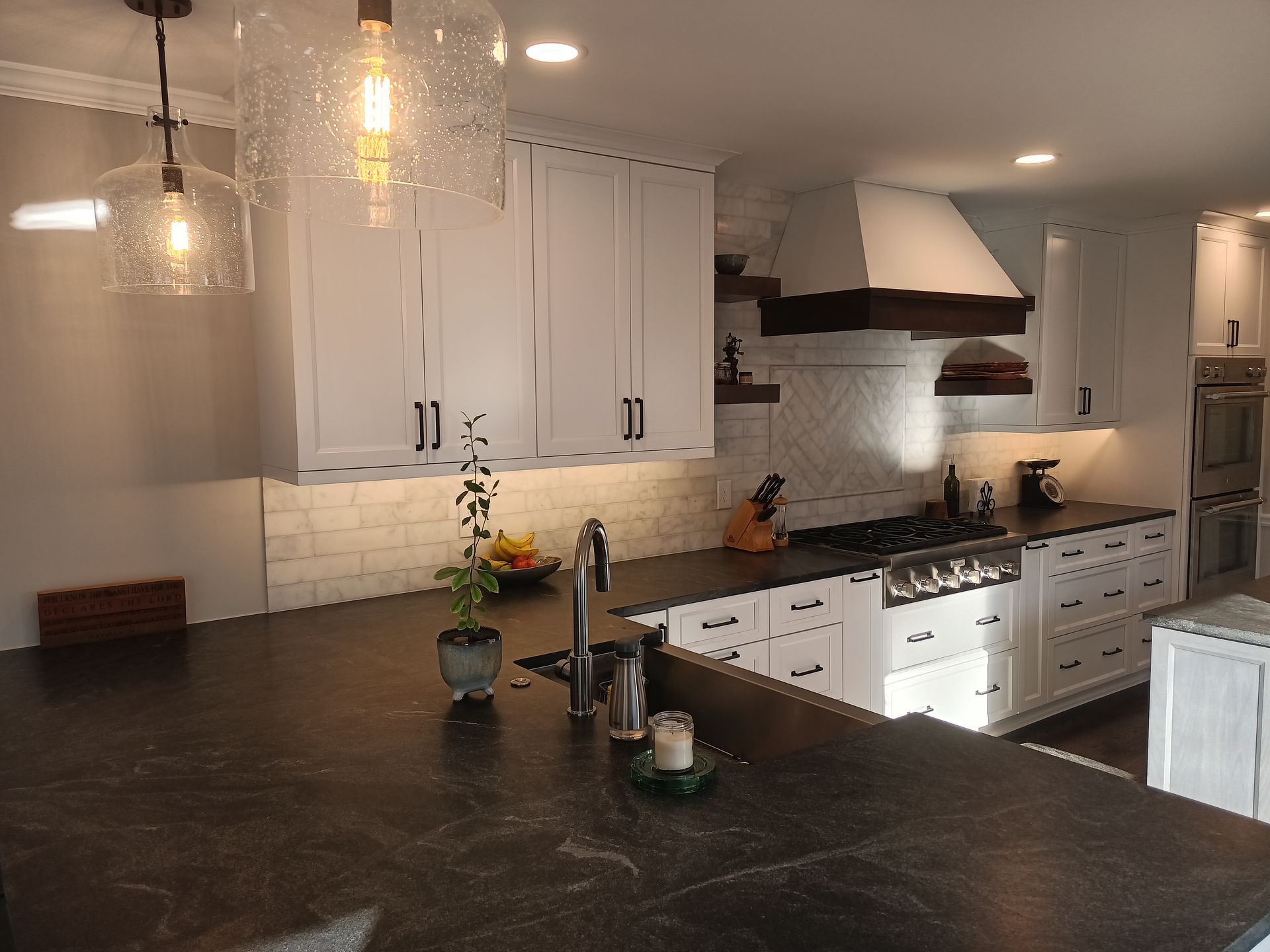 Modern kitchen with white cabinets, dark countertops, and pendant lights.
