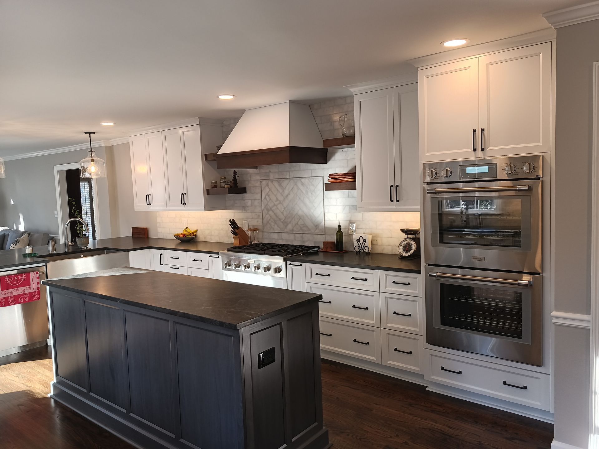Modern kitchen with white cabinets, dark island, and stainless steel appliances.