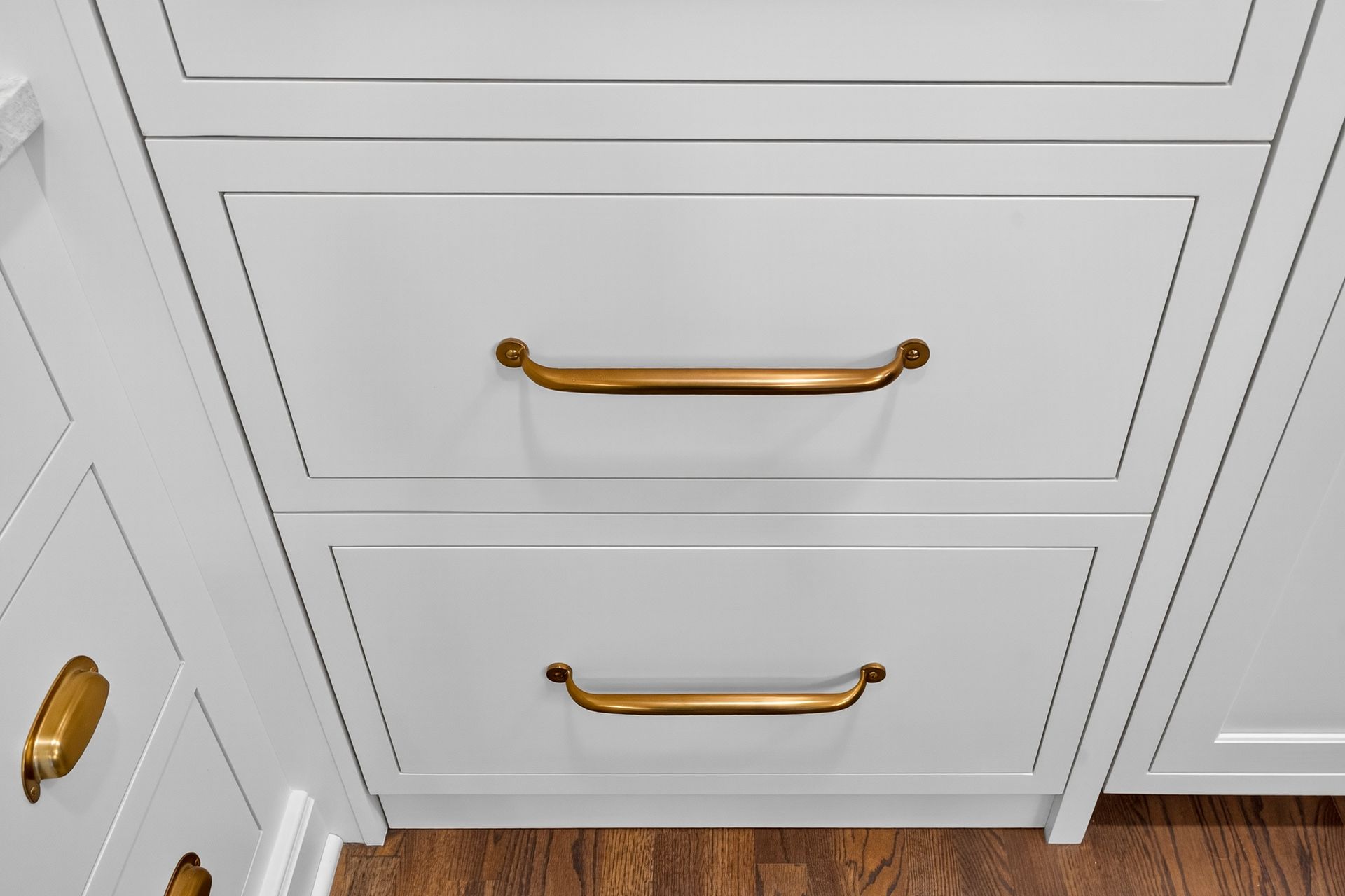 White cabinet drawers with brass handles.