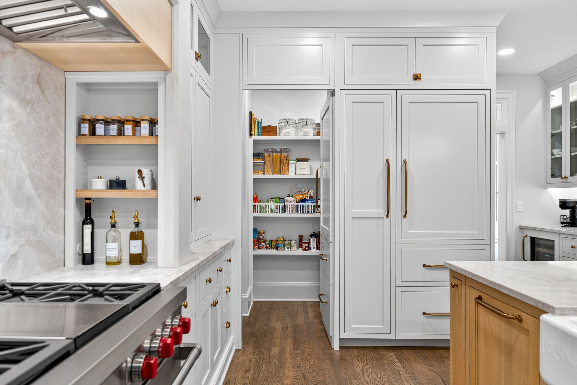 White kitchen with built-in pantry and refrigerator; wood and gold accents.