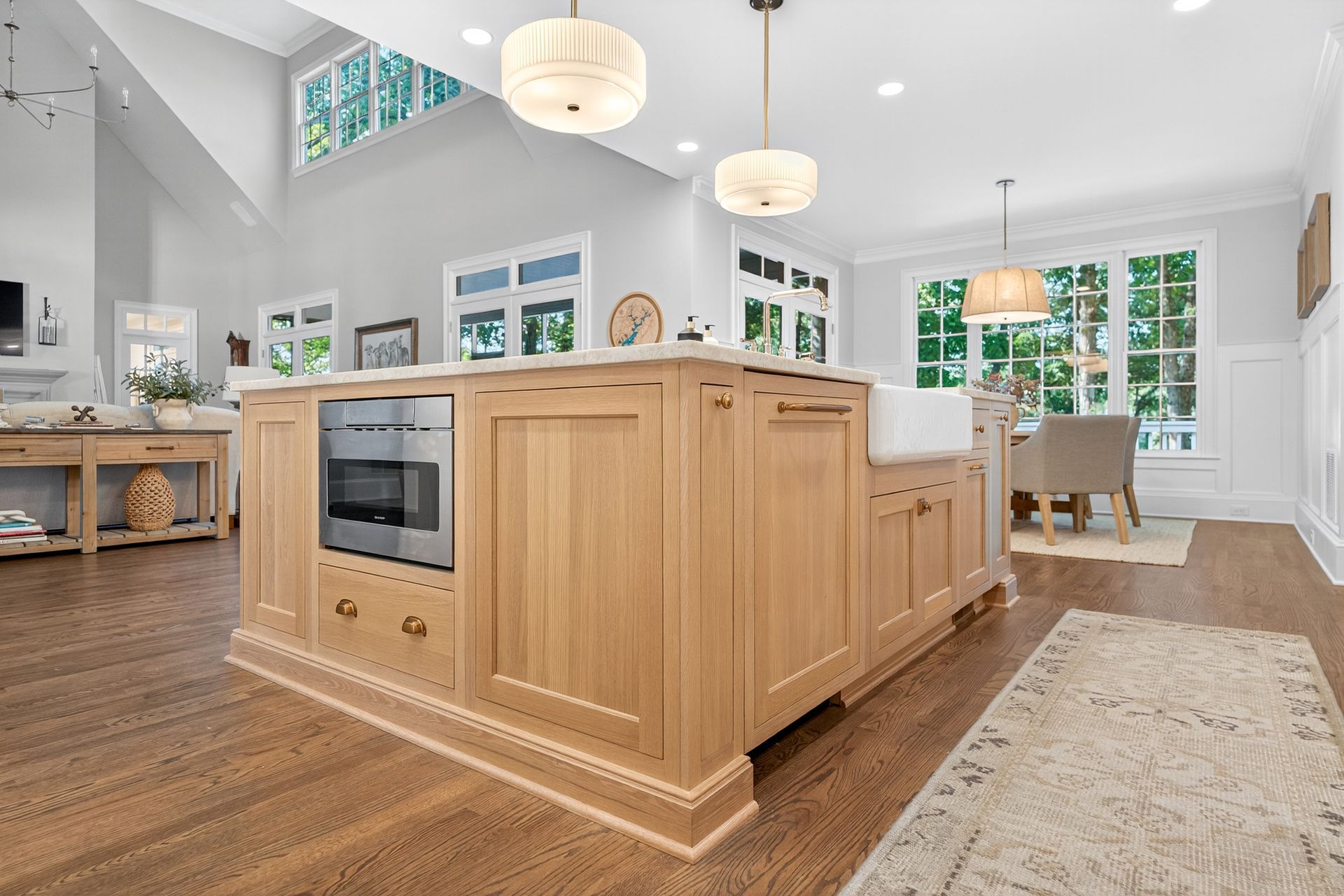 Spacious kitchen with wood island, built-in oven, pendant lights, and dining area with large windows.