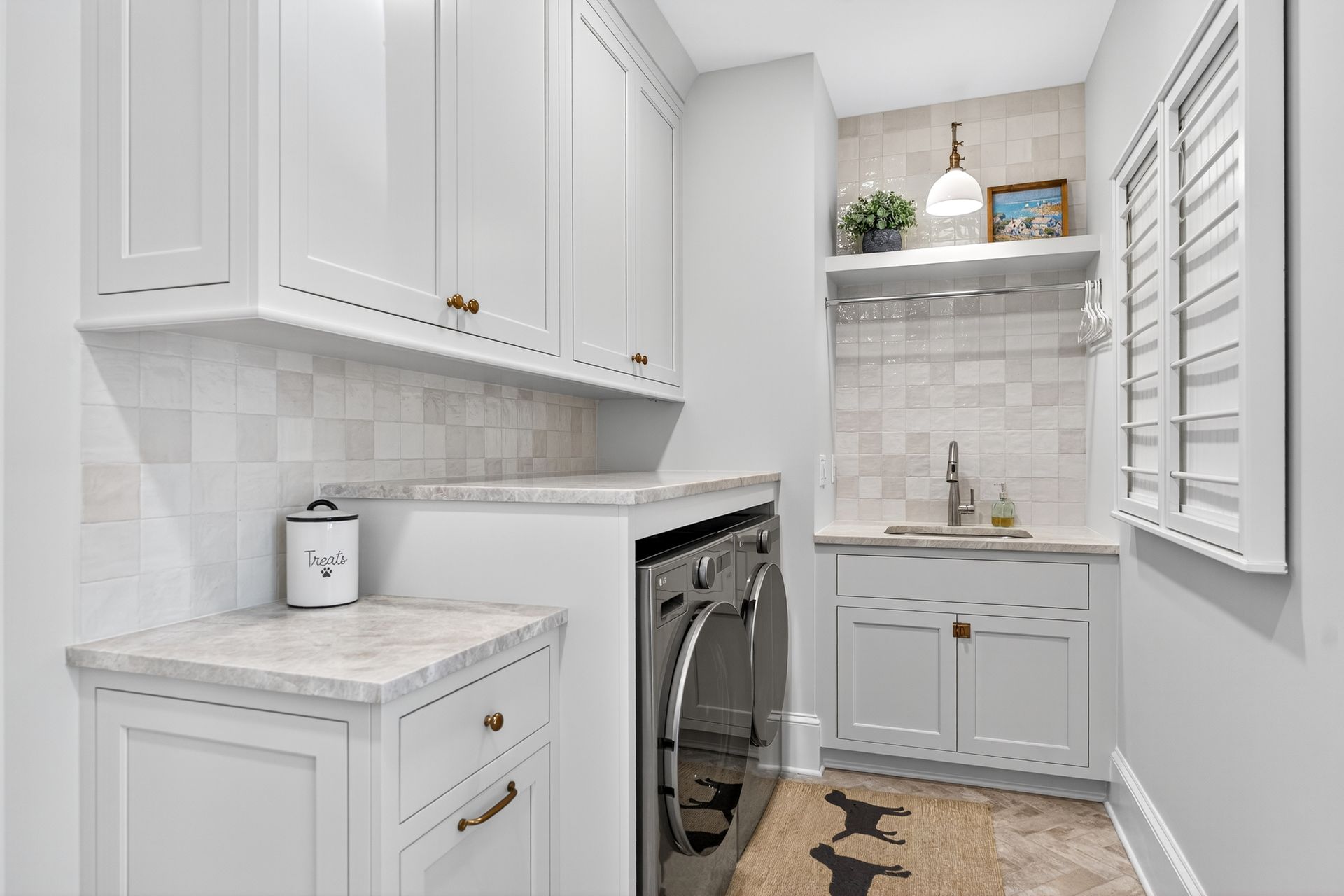 Laundry room with white cabinets, light countertop, silver appliances, and small sink.