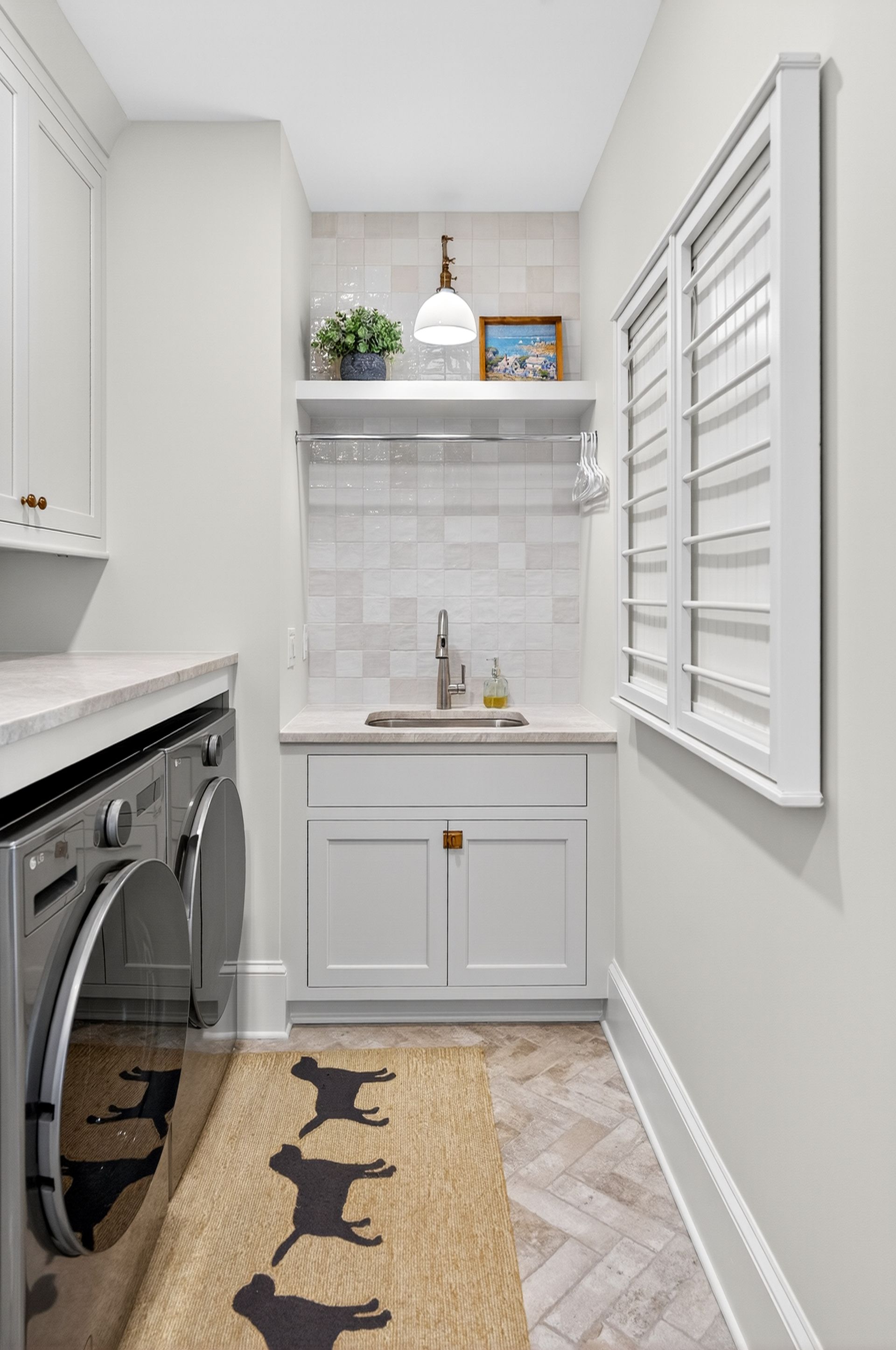 Laundry room with gray cabinets, sink, washer/dryer, and a decorative rug.