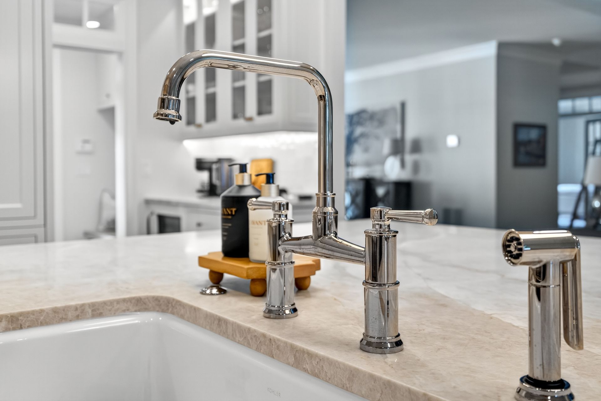 Shiny kitchen faucet with sprayer on a light countertop near a sink.