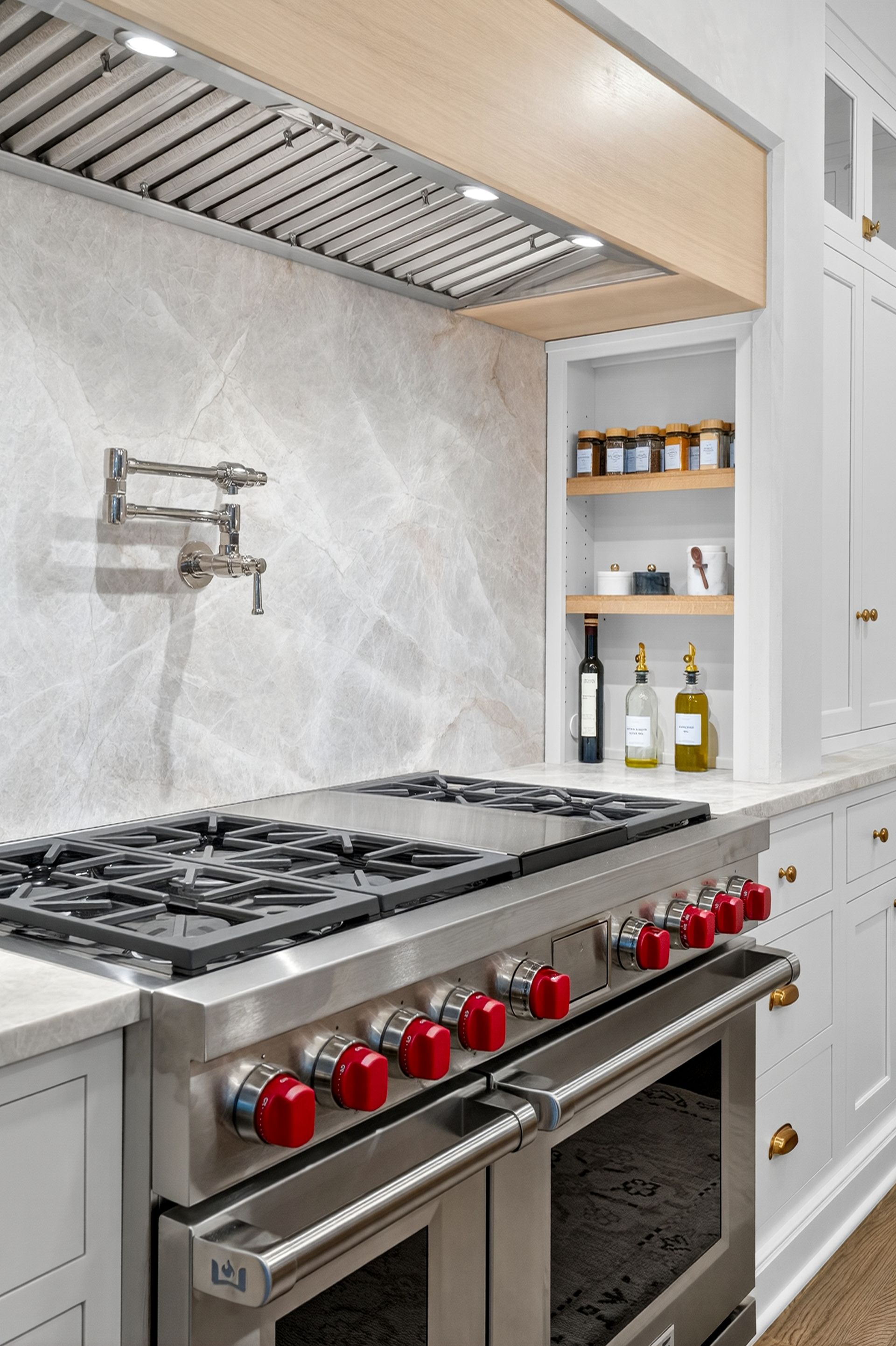 Stainless steel range with red knobs in a white and gray kitchen.