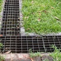 Metal grate drainage channel beside green grass lawn corner