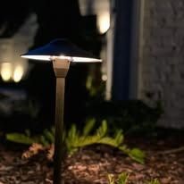 Small solar garden pathway light glowing in a landscaped yard at night