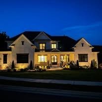 Illuminated suburban house at dusk with warm lights glowing through the windows