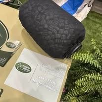 Black quilted pouch beside a white card on a table with greenery nearby