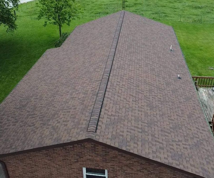 An aerial view of a brick house with a roof that is covered in shingles.