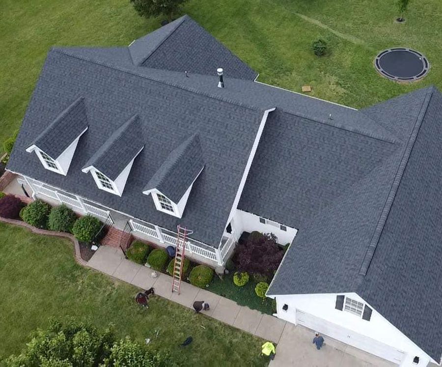 An aerial view of a large white house with a gray roof.